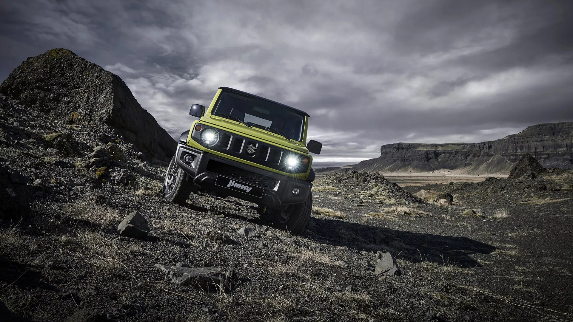 Front view of Suzuki Jimny driving off-road, showcasing its flat bonnet, cutaway bumpers and compact 4x4 agility.