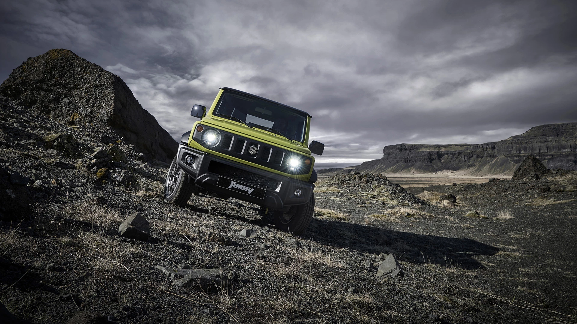 Front view of Suzuki Jimny driving off-road, showcasing its flat bonnet, cutaway bumpers and compact 4x4 agility.
