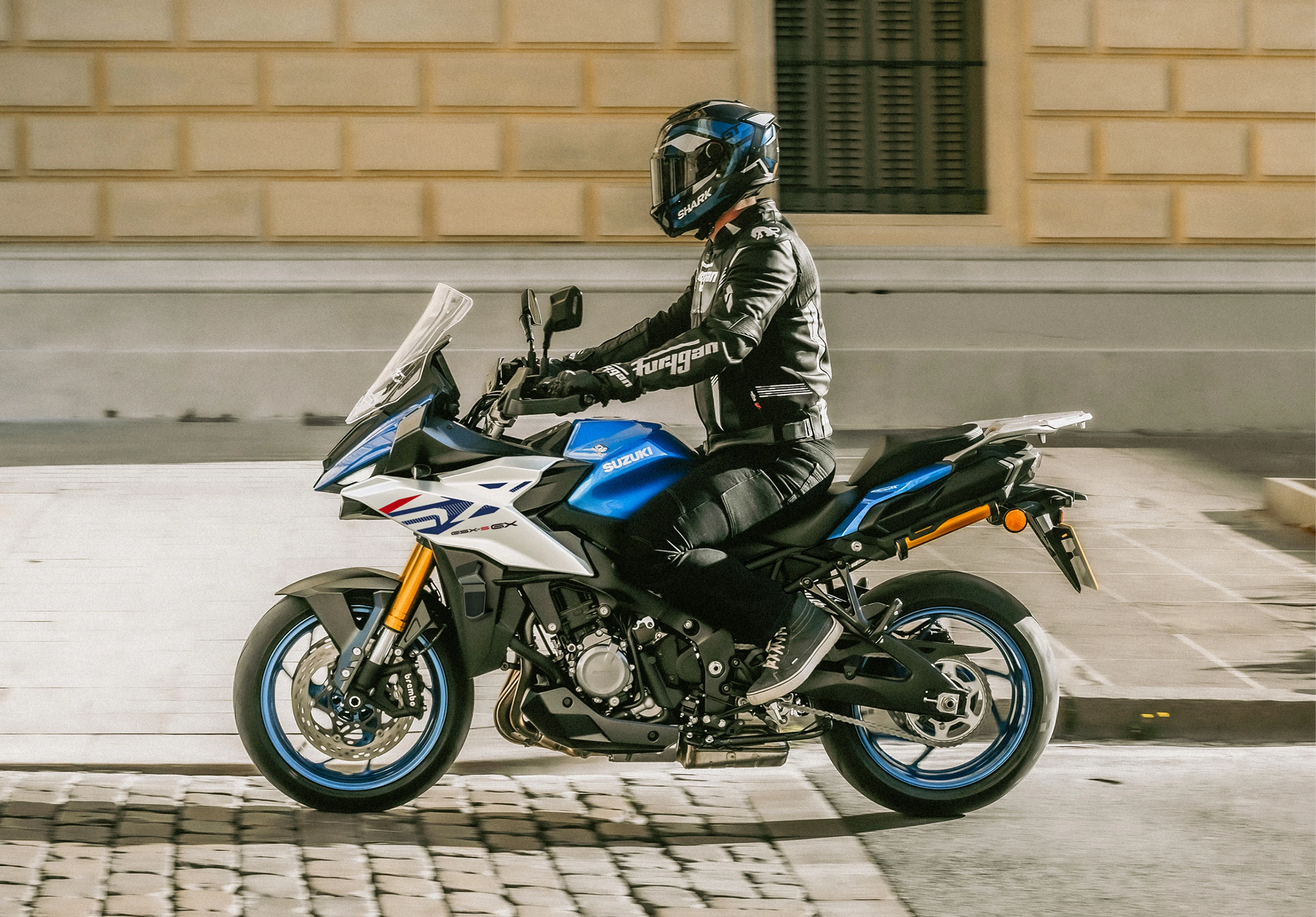 Suzuki GSX-S1000GX+ on a mountian road leaning hard into a corner.