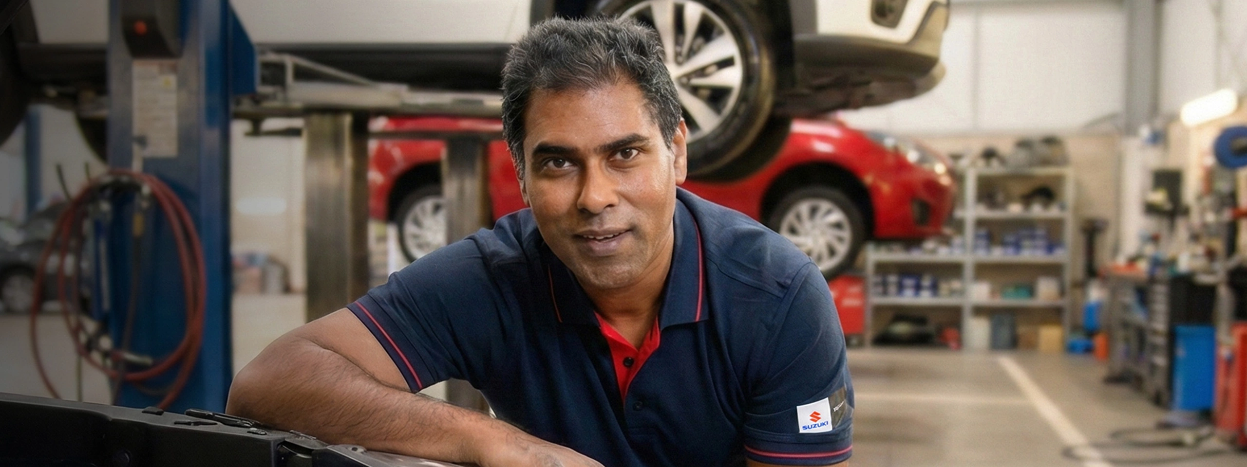 Suzuki service technician working on a car in a workshop