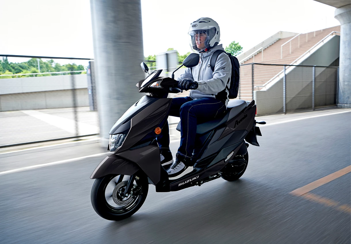 Suzuki Avenis 125 front three quarters riding through a city underpass
