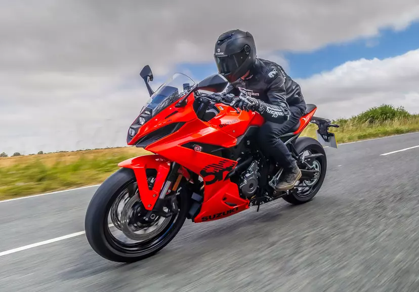 Suzuki GSX-8R leaning heavily into a corner with a sunny country road backdrop
