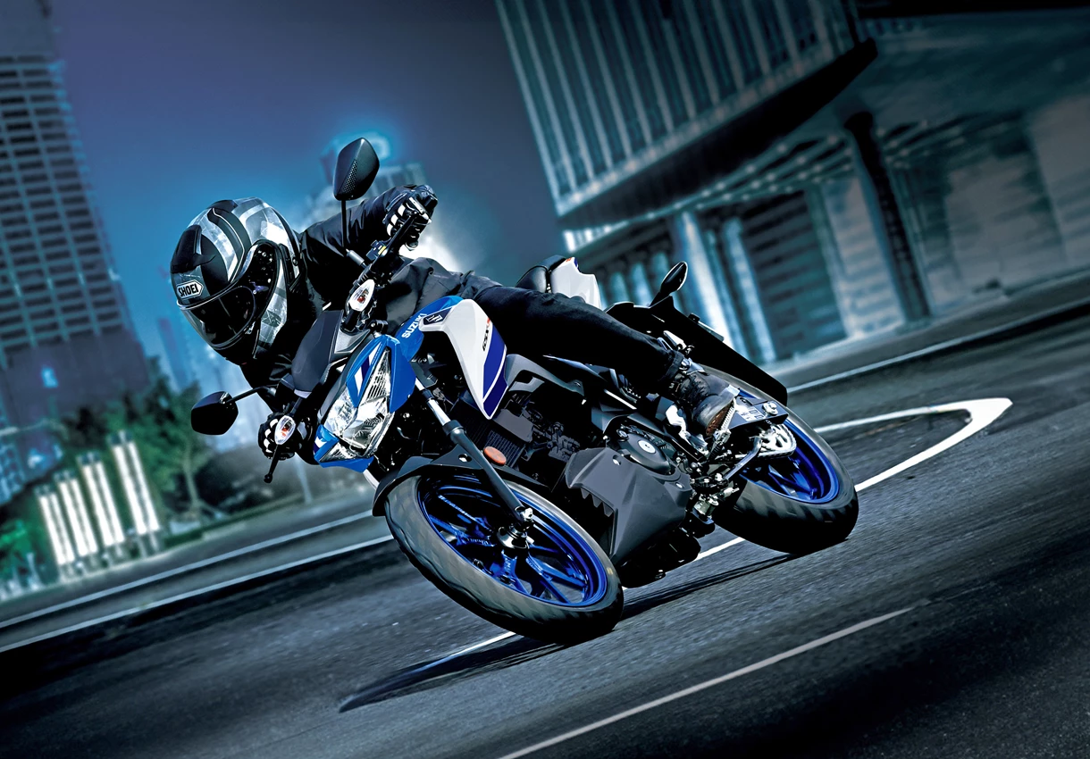 Suzuki GSX-S125 at night leaning into a corner with a city background.