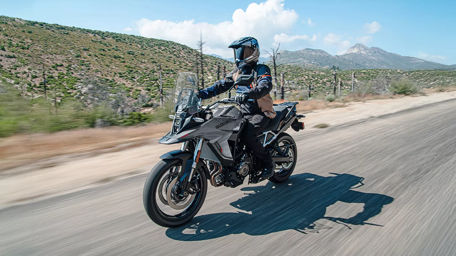 Suzuki V-Strom 800RE grey riding along a mountain road.