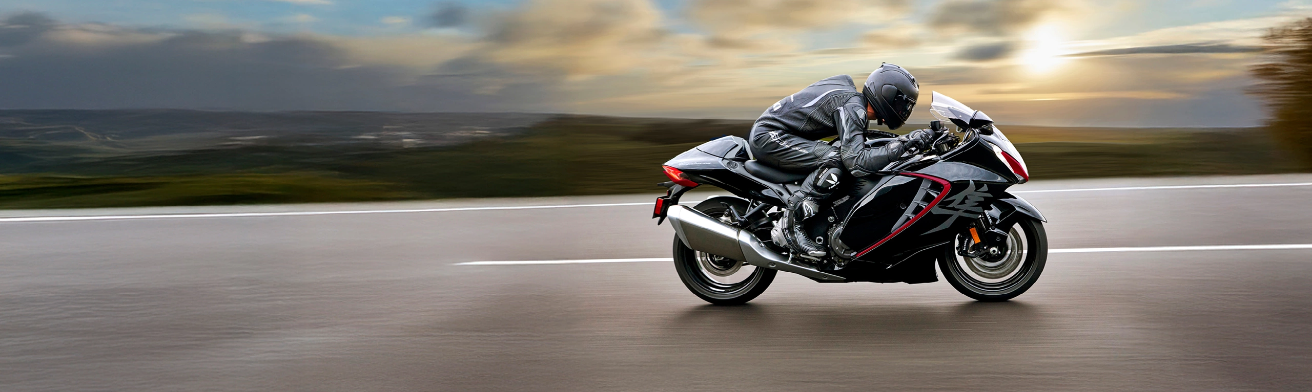 Suzuki Hayabusa black moving along a road with a sunset background