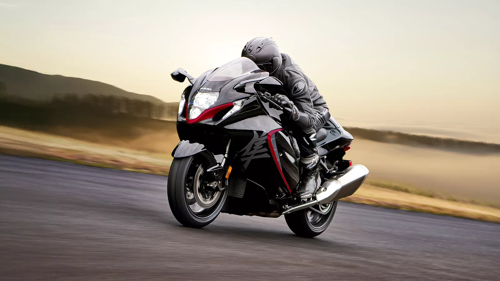 Suzuki Hayabusa black moving along a runway with a sunset behind.