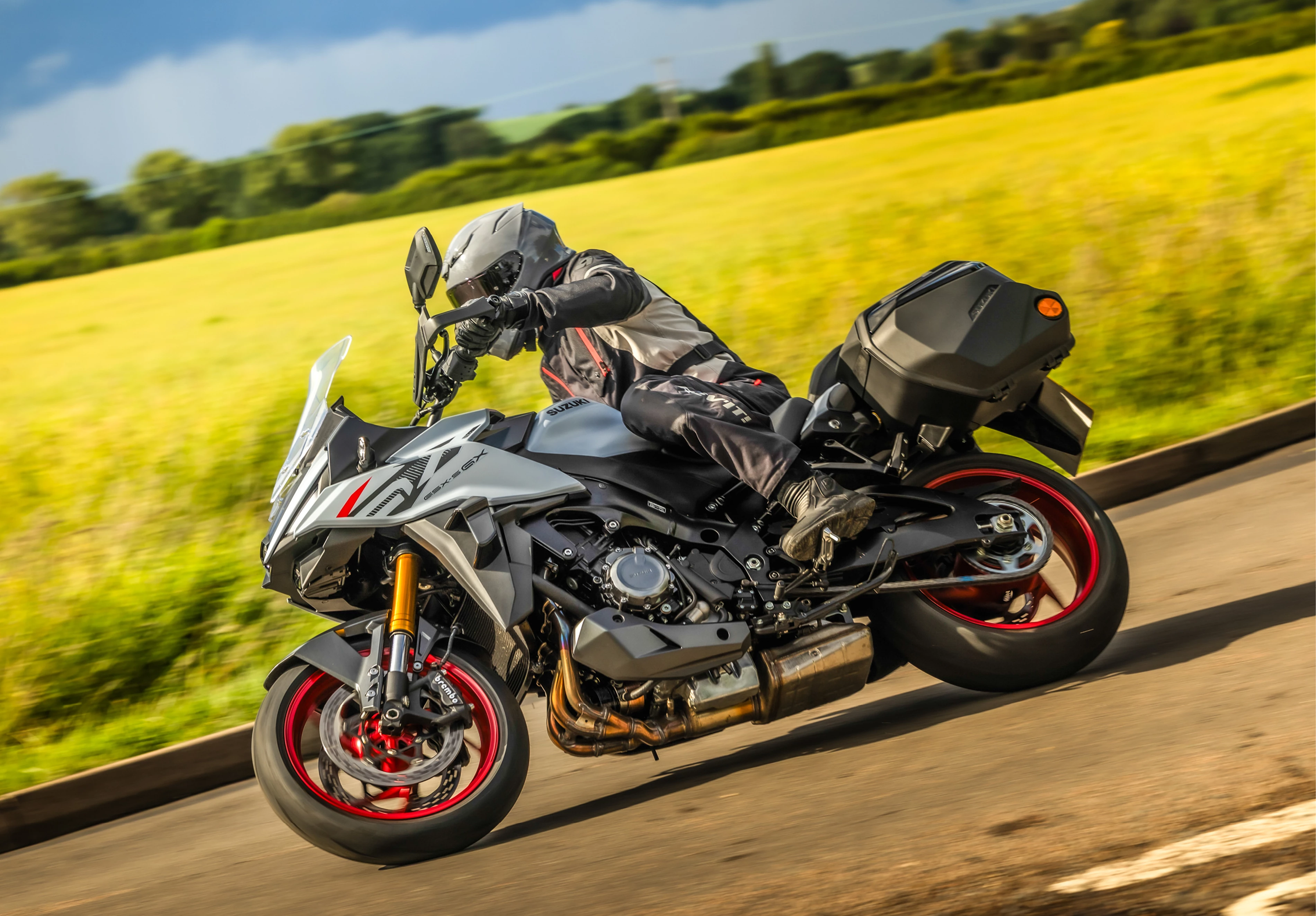 Suzuki GSX-S1000GX+ leaning into a corner with a field behind