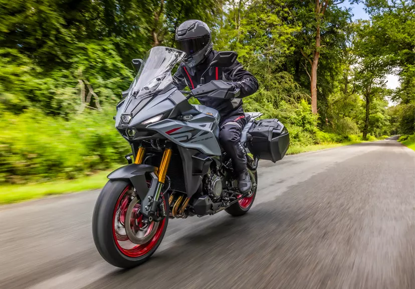 Suzuki GSX-S1000GX+ heading along a tree lined road. 