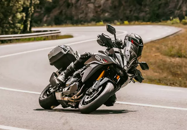 Suzuki GSX-S1000GX+ on a mountian road leaning hard into a corner.