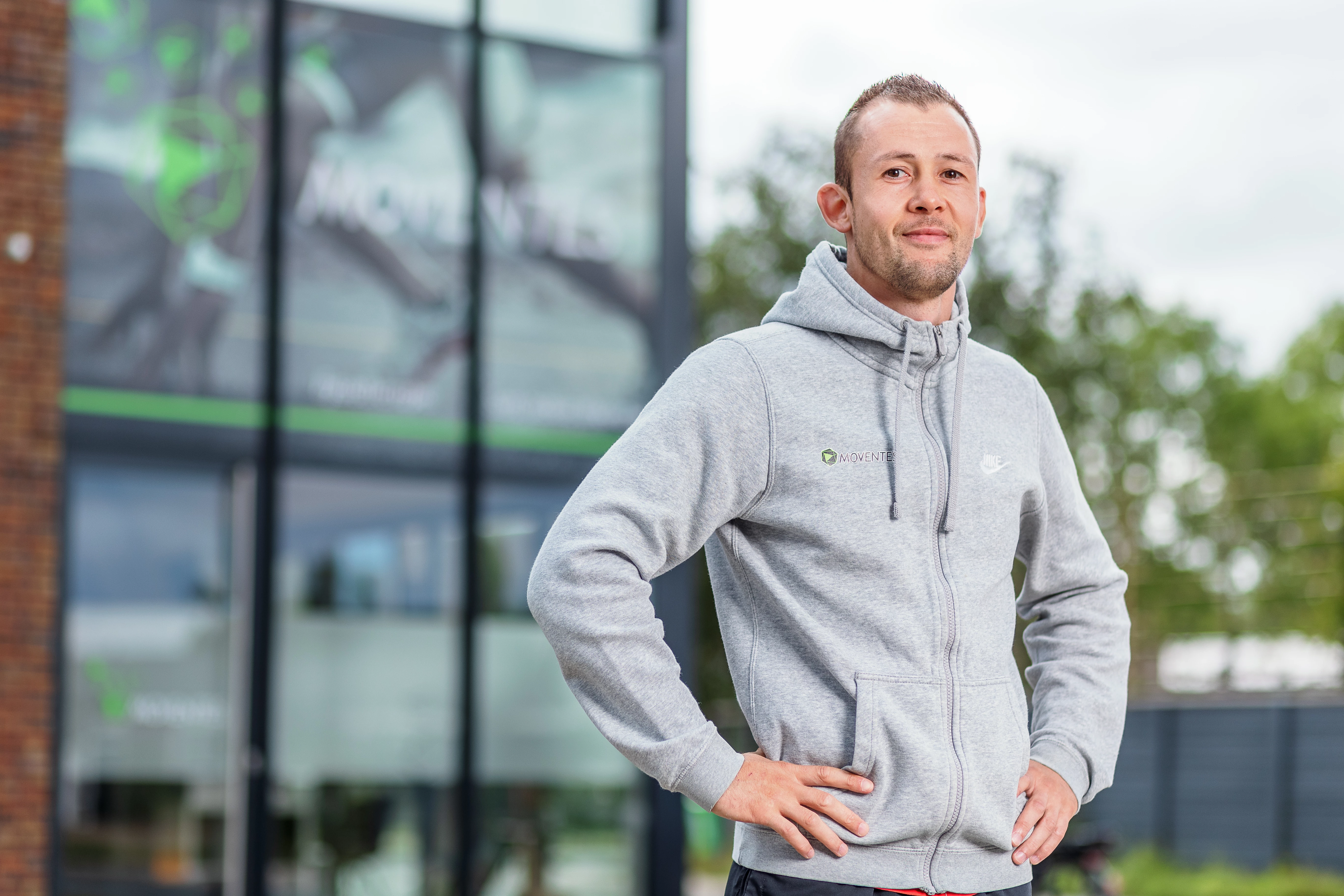 Zelfstandige fysiotherapeut staat met trots voor zijn fysiopraktijk 