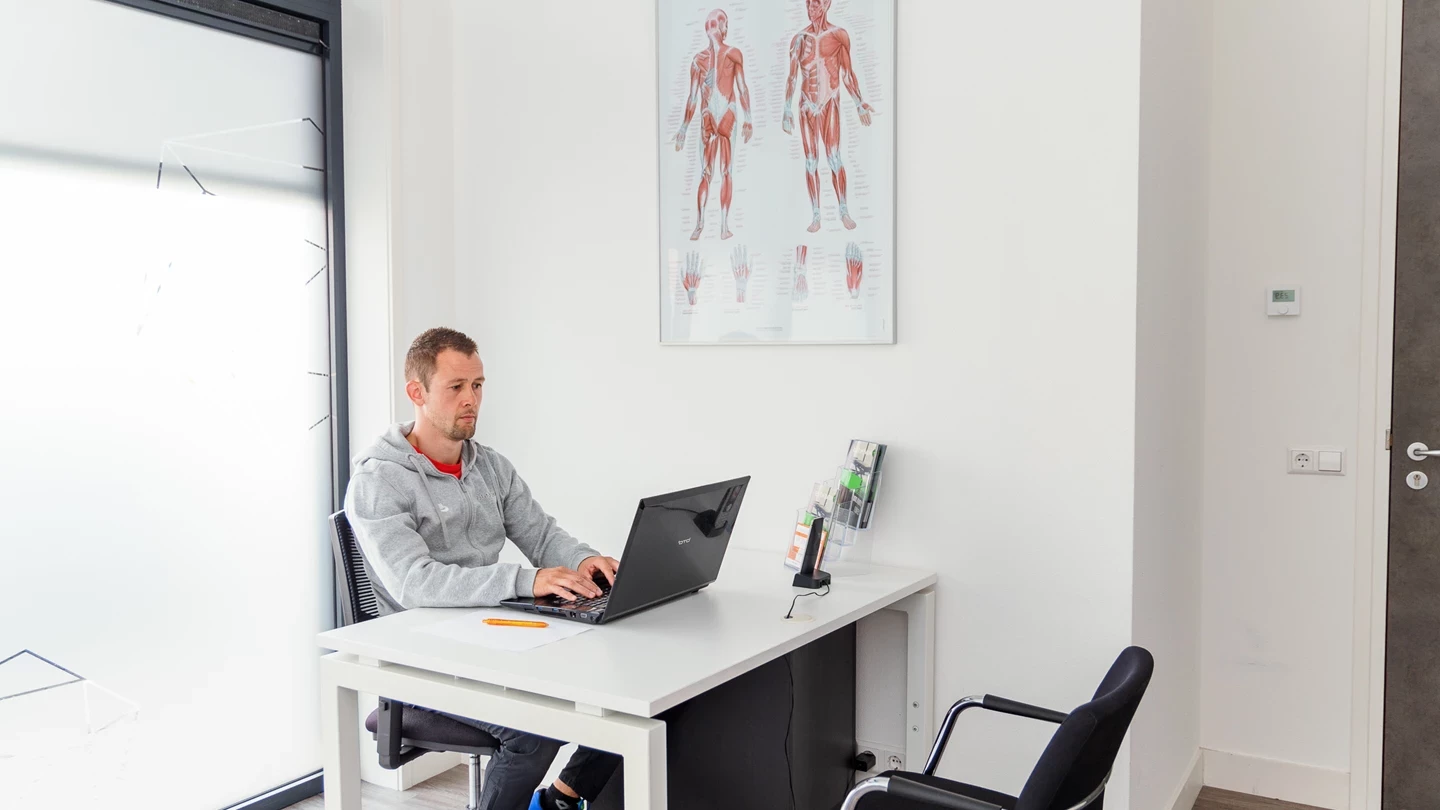 Fysiotherapeut in zijn praktijk achter bureau