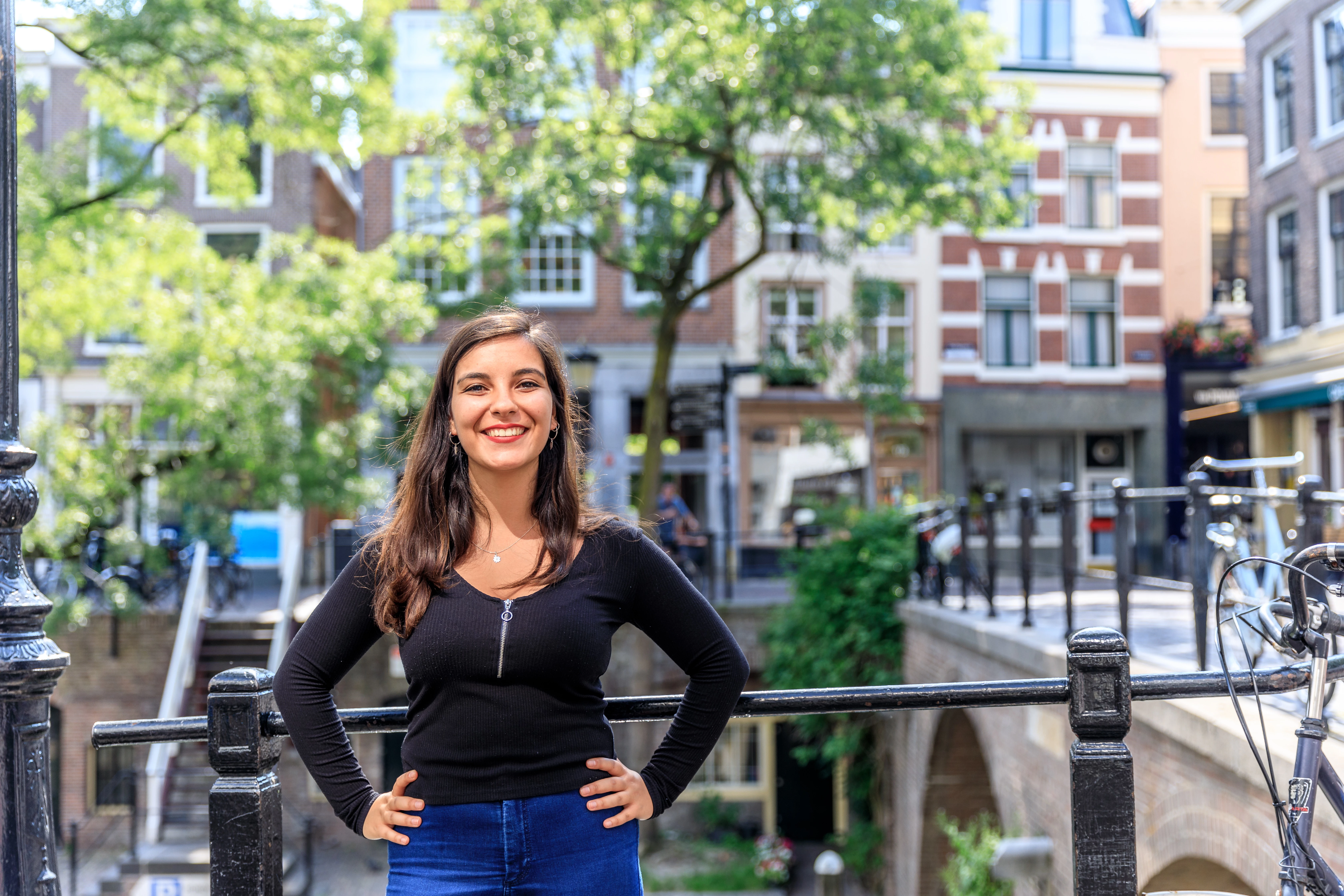 Student staat met armen in haar zij en kijkt zelfverzekerd naar camera