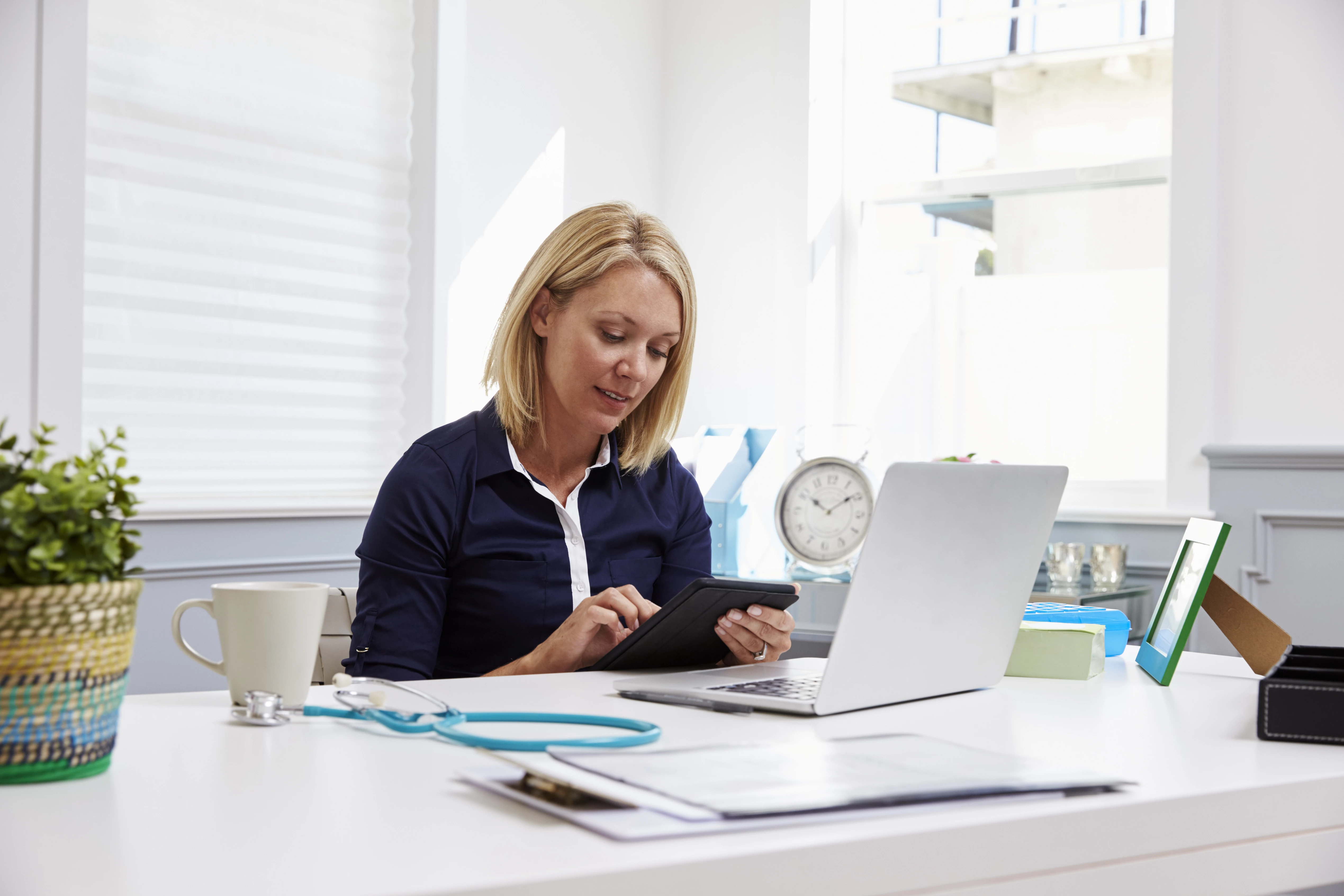Huisarts leest in haar huisartsenpraktijk tussen de afspraken door hoe het zit met met aansprakelijkheid en verkapt dienstverband bij zzp'ers.