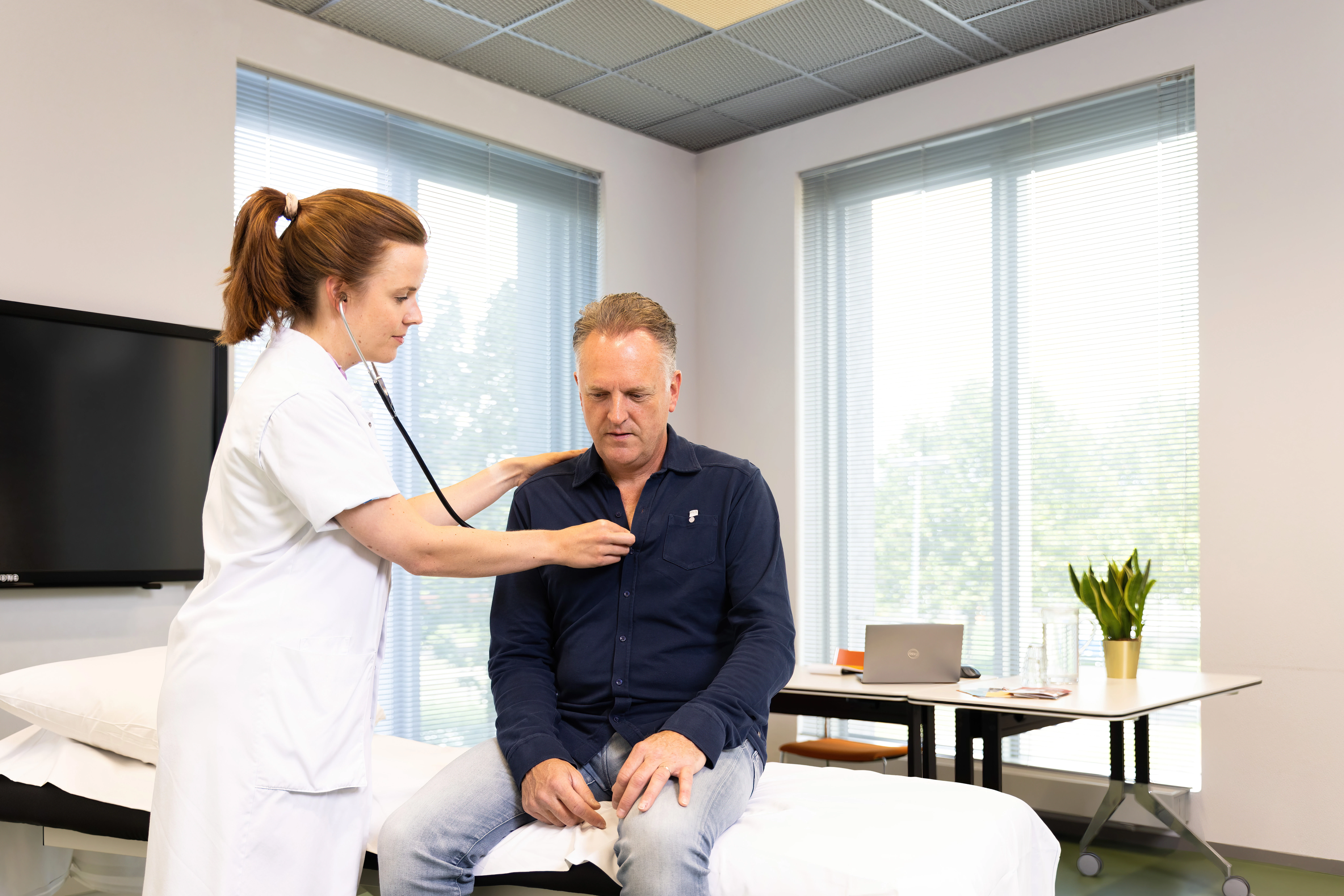 Patiënt heeft een consult bij de huisarts waar zijn hartslag wordt gecontroleerd.