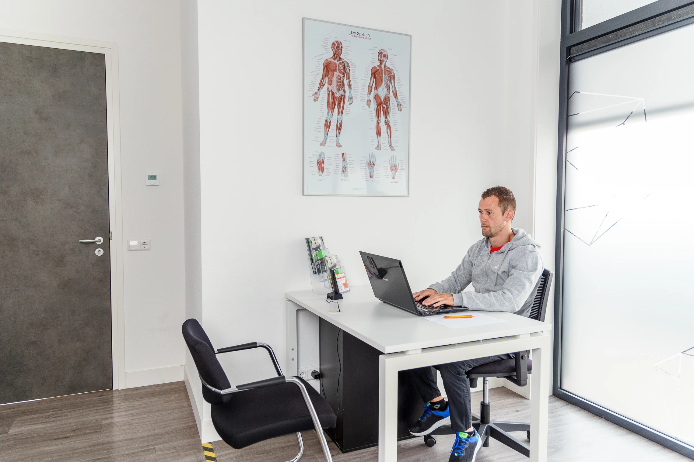 Man achter bureau in eigen praktijk