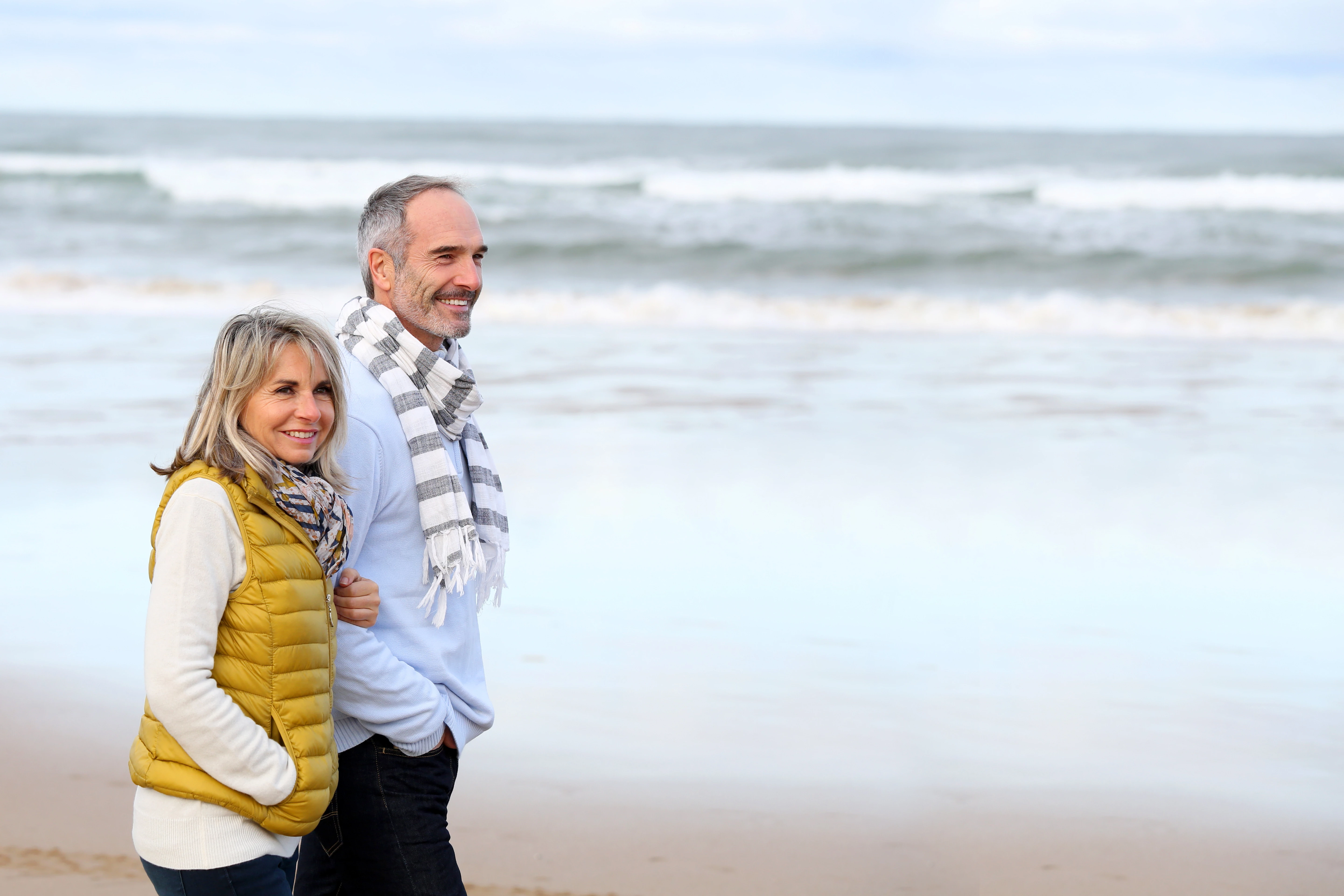 Ouder echtpaar wandelt samen over het strand