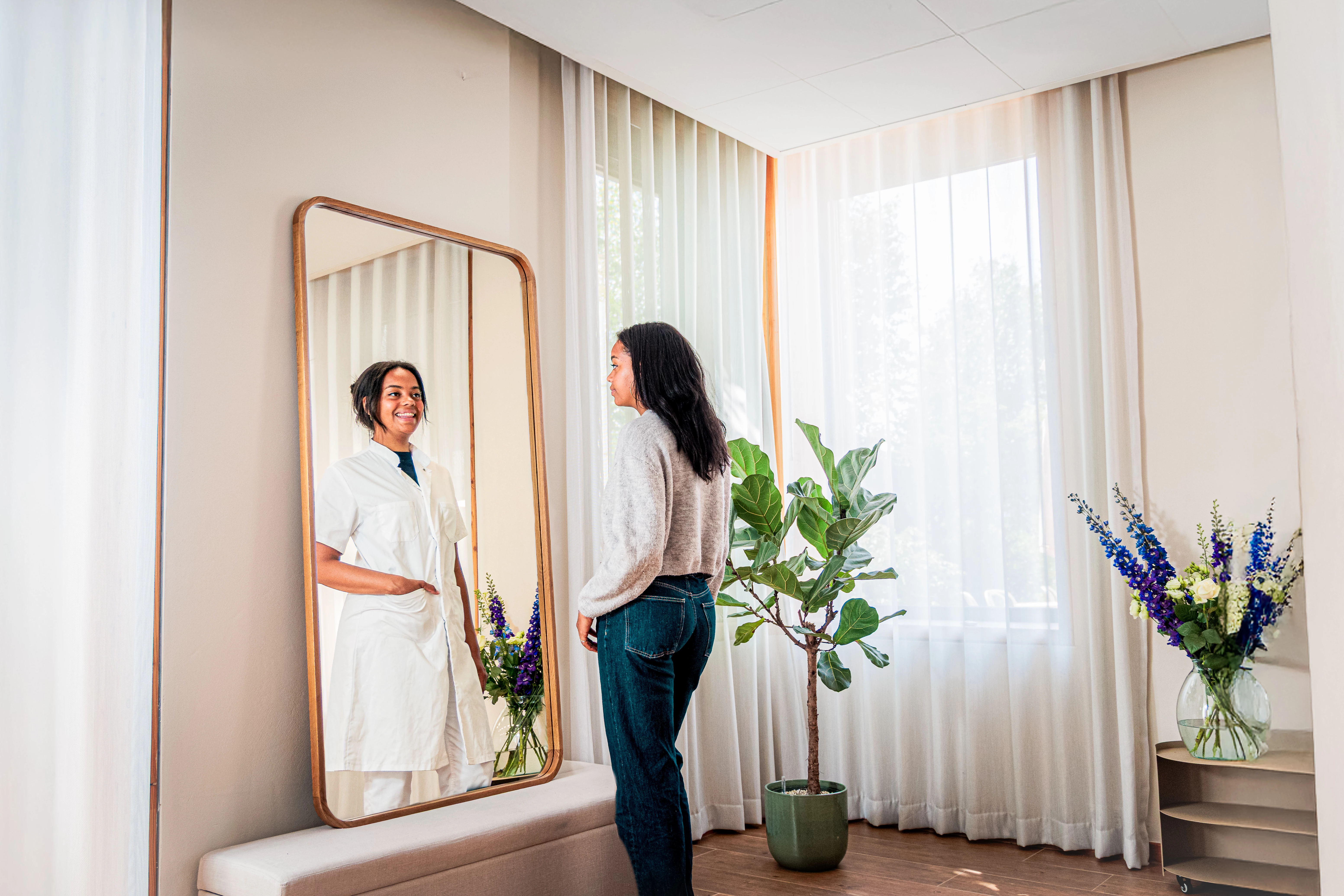 Een vrouwelijke tandarts staat voor de spiegel klaar voor haar carrière als tandarts