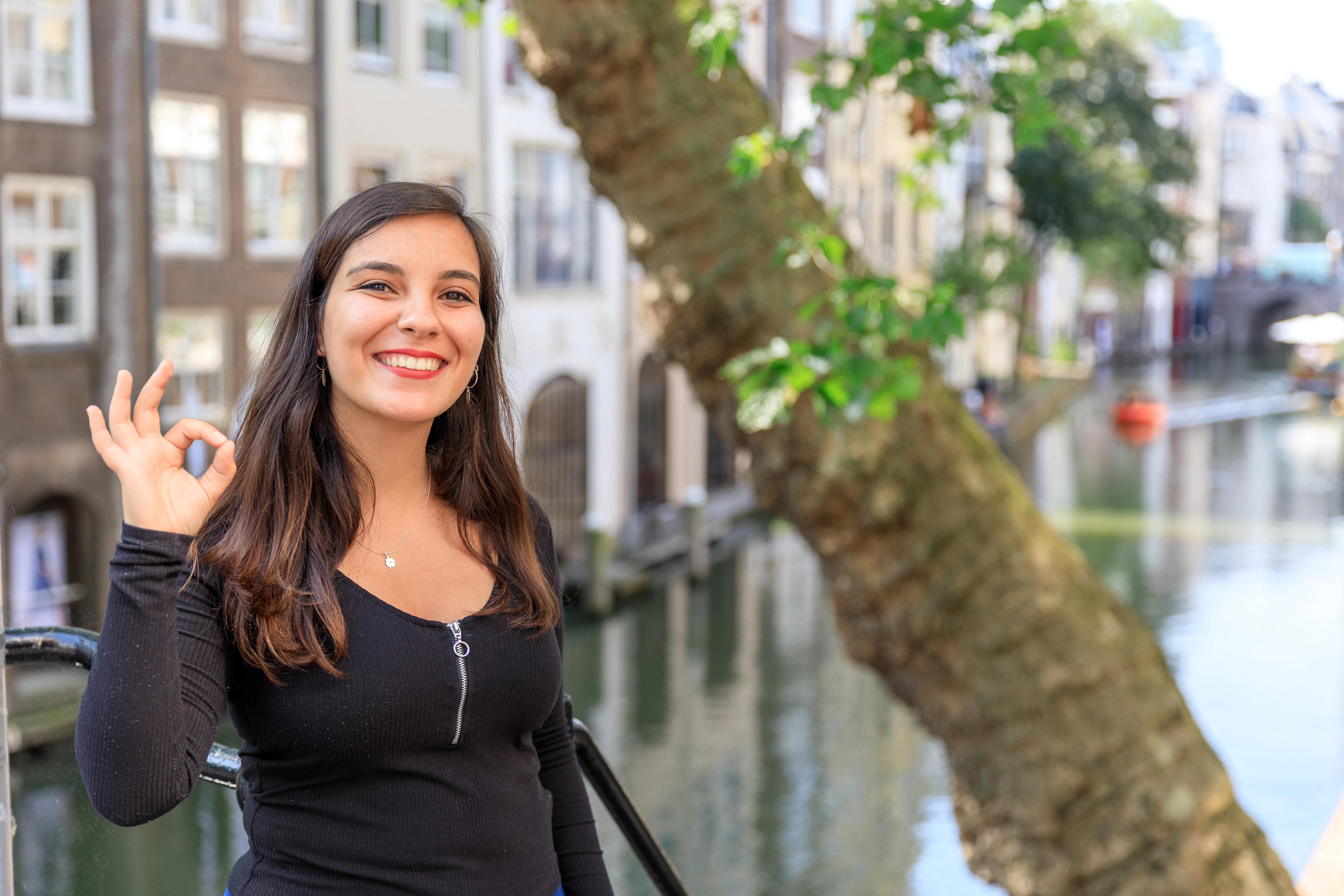 Studente staat buiten en lacht.