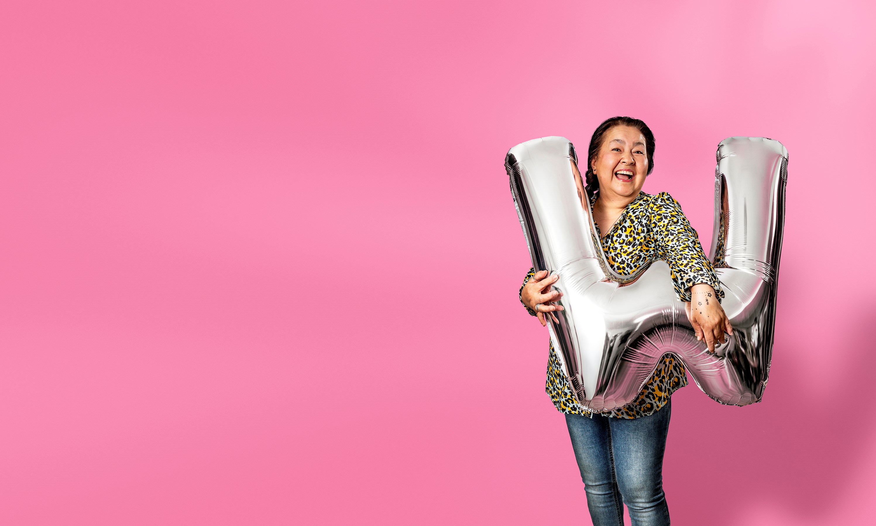 Vrouw met donker haar houdt zilveren ballon in W-vorm vast