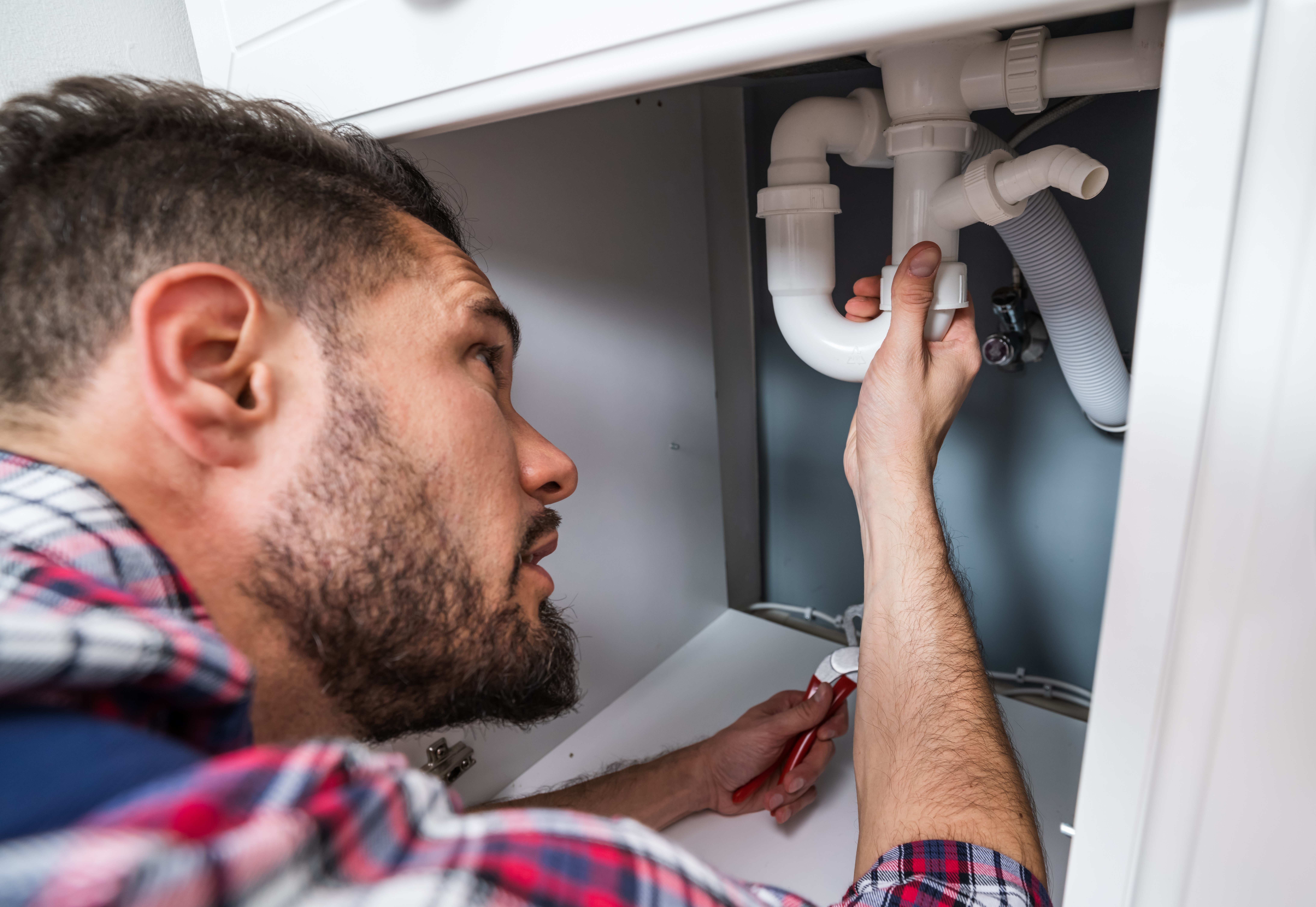 Loodgieter repareert sifon onder gootsteen